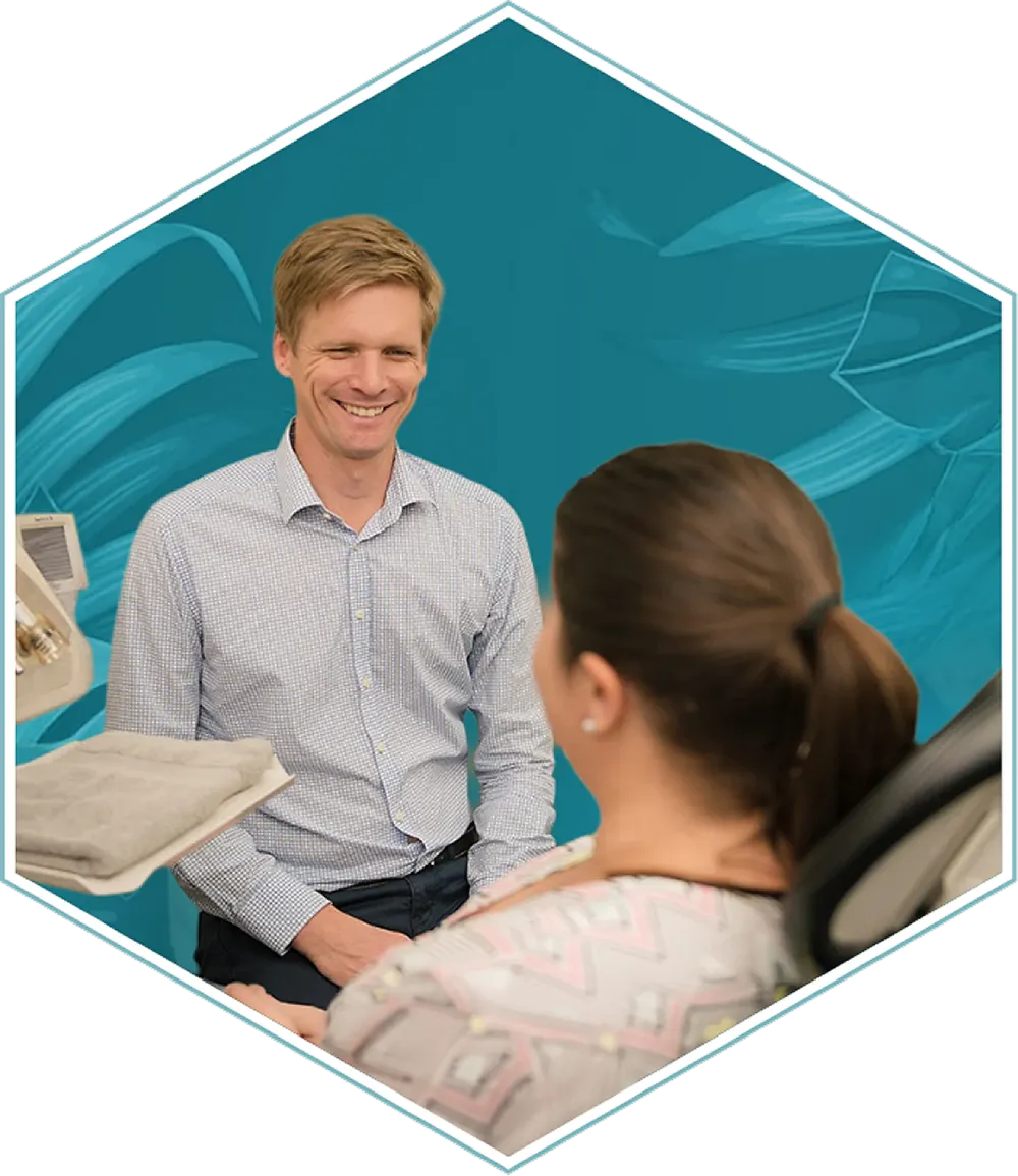 Dr Lincoln speaking with a seated person in a dental treatment room at Harris Dental Boutique.