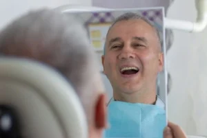patient checking his teeth after a dental procedure patient checking his teeth after a dental procedure